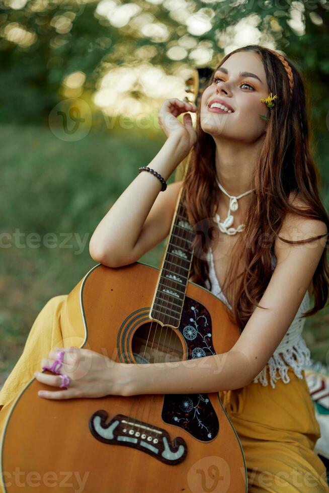 hippie eco amigáveis mulher com uma guitarra relaxante dentro natureza sentado em uma xadrez de a lago dentro a tarde dentro a raios do a configuração Sol. uma estilo de vida dentro harmonia com a corpo e natureza foto