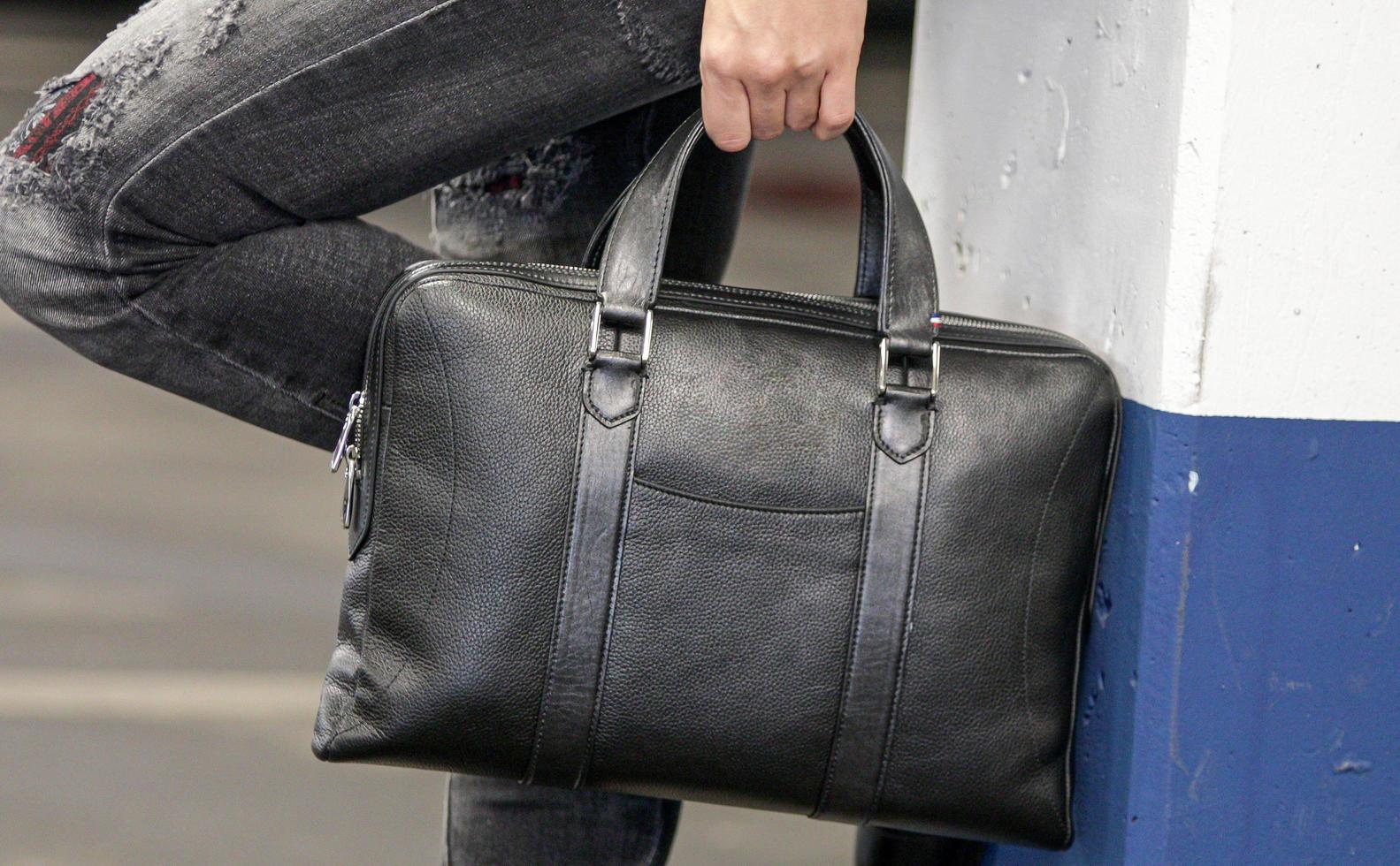 imagem recortada de uma mulher elegante segurando uma grande bolsa de couro preta foto