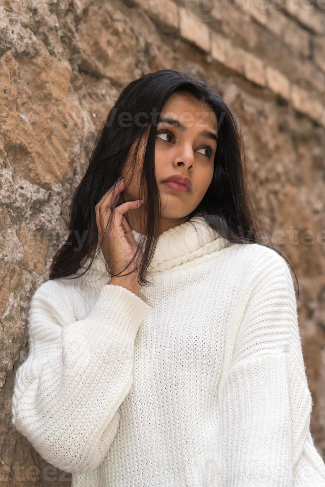 mulher morena pensativa e contemplativa, vestindo uma blusa de gola alta ou um suéter olhando para o lado foto