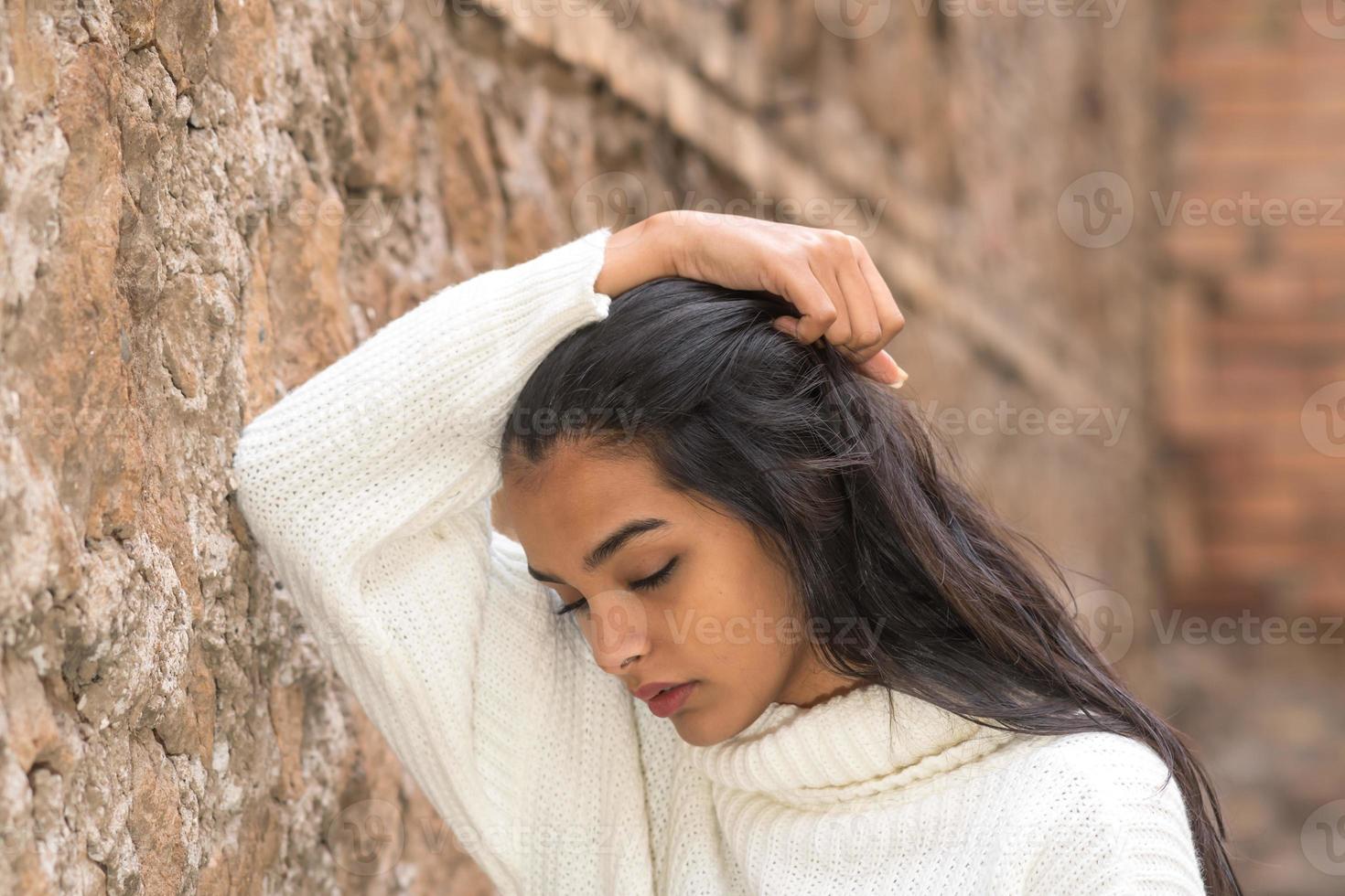 retrato de uma mulher morena romântica com a mão no cabelo a desviar o olhar foto