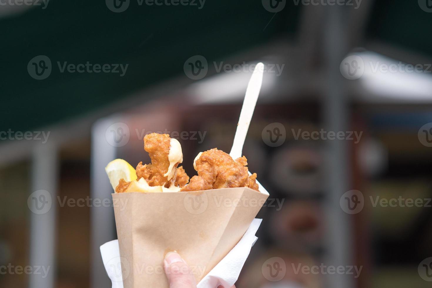 mão masculina segurando peixe britânico com batatas fritas em um cone de papel foto