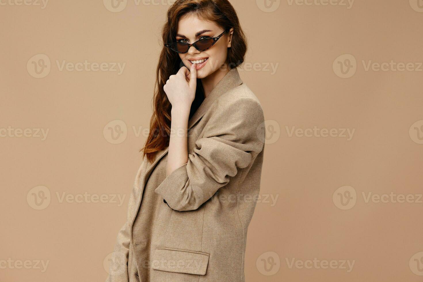 glamouroso mulher dentro bege casaco e óculos sorrir gesticulando com mãos foto