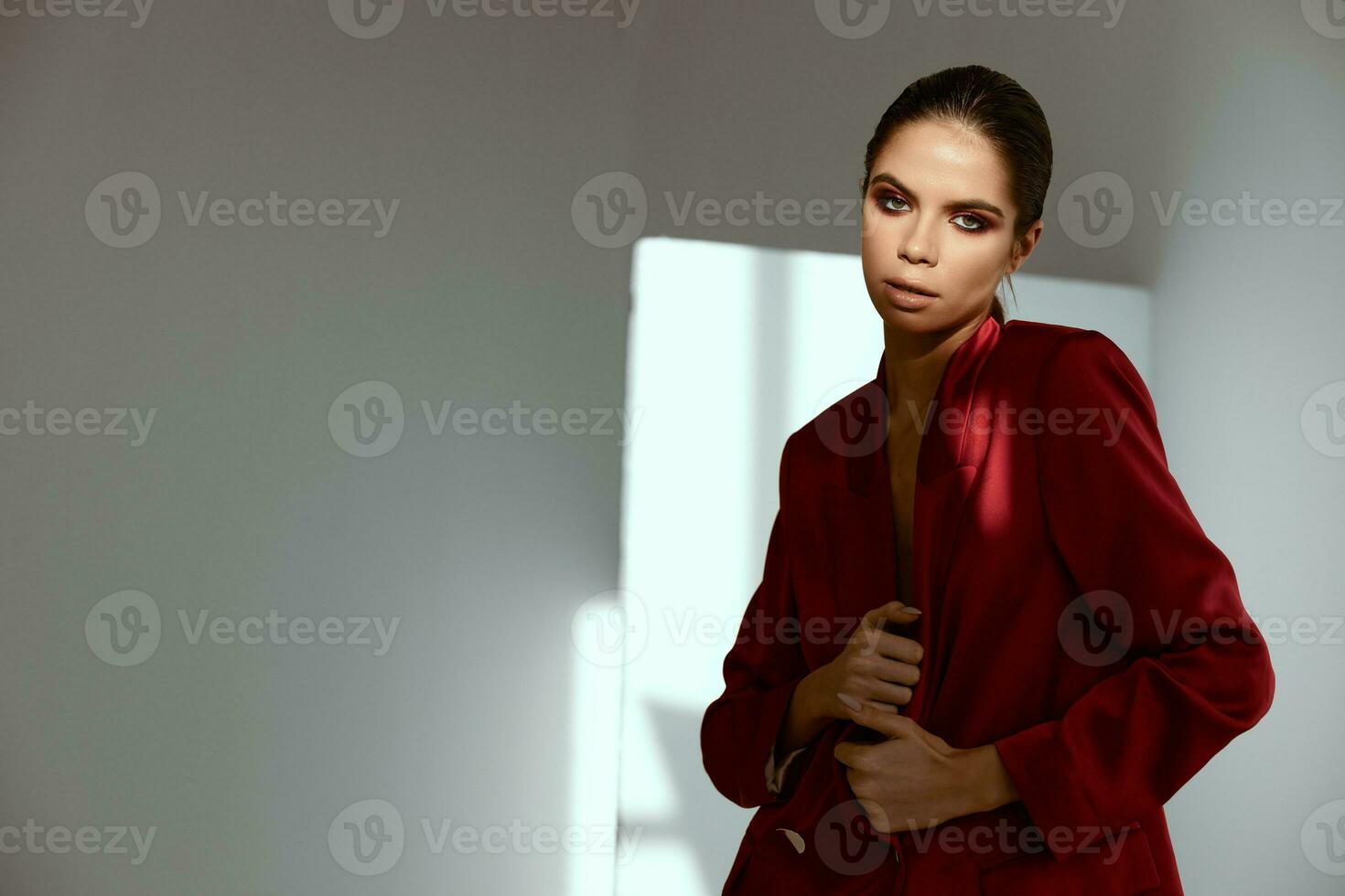 atraente mulher modelo dentro vermelho Jaqueta posando dentro uma Sombrio quarto foto