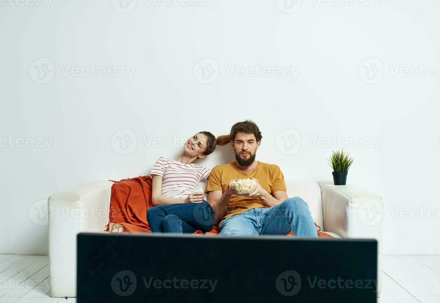 assistindo televisão casado casal homem e mulher em a sofá e uma flor dentro uma Panela foto