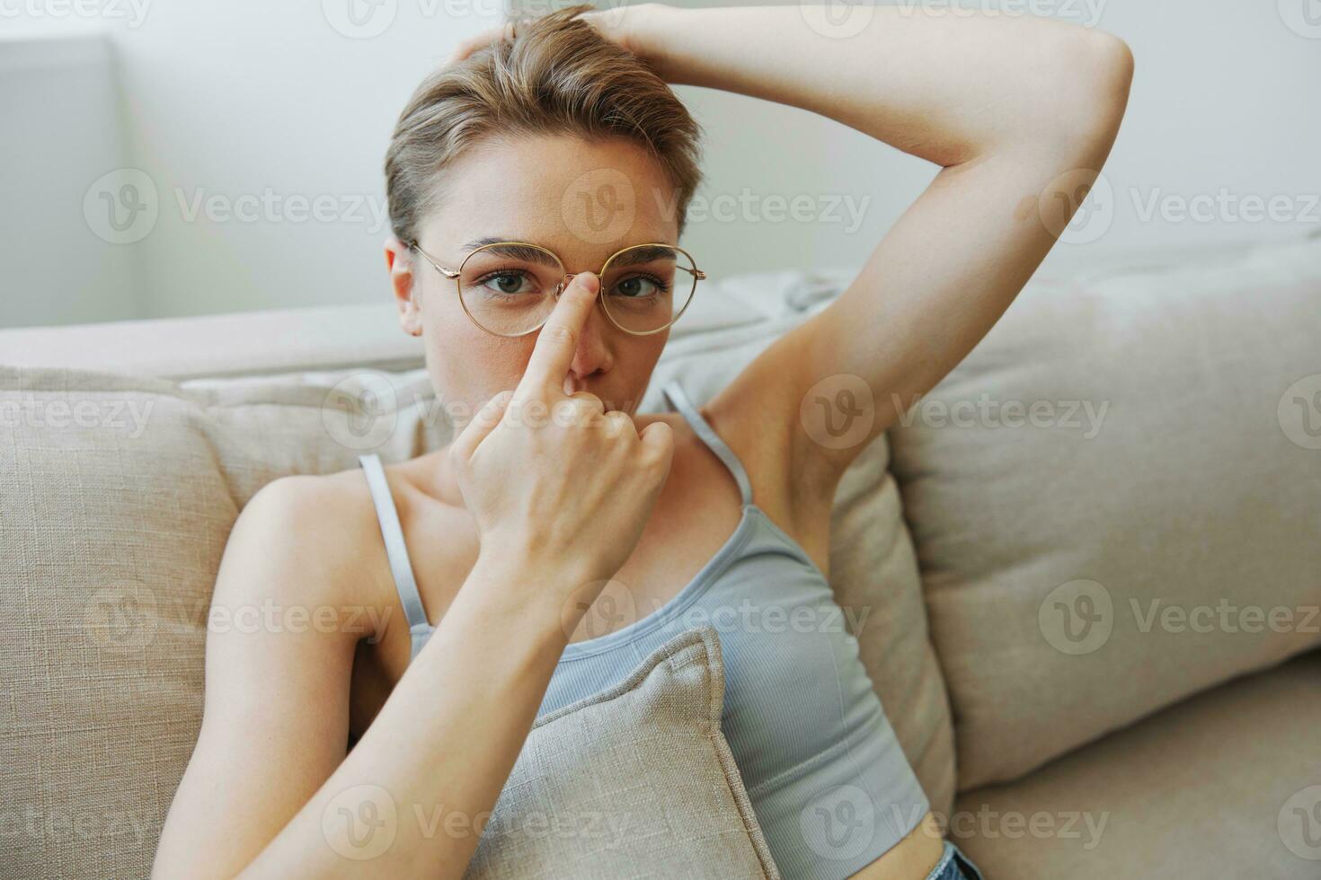uma mulher vestindo Óculos senta em uma sofá e parece às a Câmera. visão problemas foto