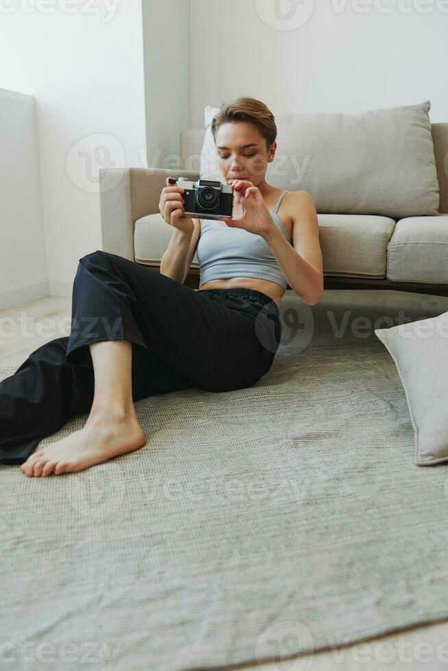 feliz sorrir mulher segurando a velho Câmera e levando As fotos do ela mesma Como uma final de semana fotógrafo dentro casa roupas com uma curto corte de cabelo cabelo sem filtros em uma branco fundo, livre cópia de espaço