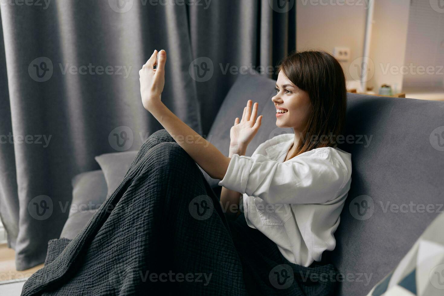 ruivo mulher com uma telefone dentro dela mão senta em a sofá e uma xadrez em dela joelhos conforto conveniência foto