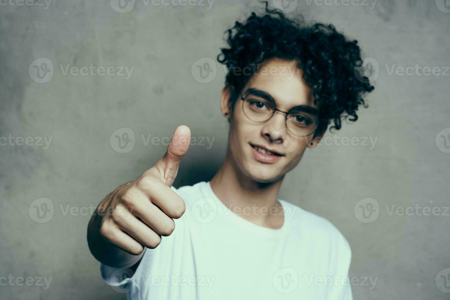 engraçado cabelo encaracolado cara gesticulando com dele mão vestindo óculos emoções cortada Visão foto