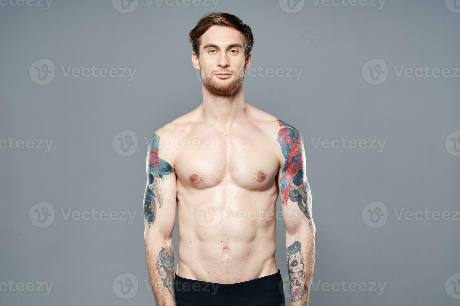 desportivo homem com uma nu tronco bombeado acima pressione tatuagens em dele braços foto