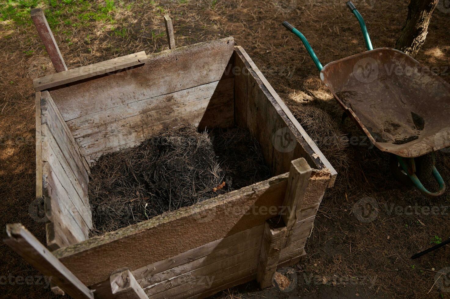 composto pilha. composto Cova em a enredo do terra. de madeira caixa para fertilizante e desperdício. húmus com seu próprio mãos. foto