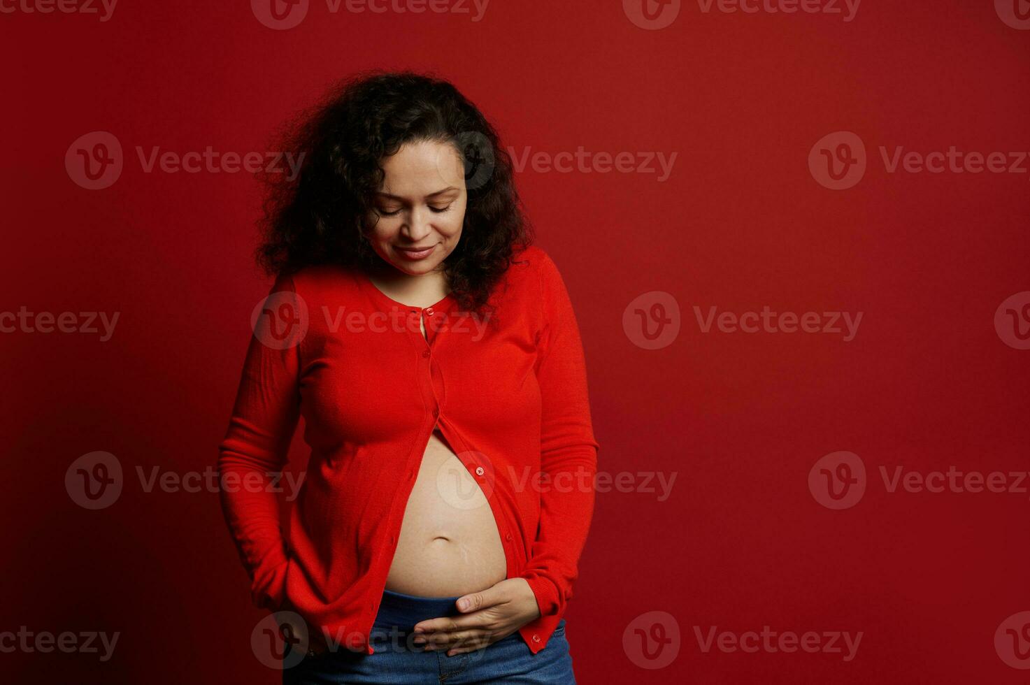 africano americano positivo grávida mulher tocante dela barriga, sorridente, isolado em vermelho fundo com cópia de de Anúncios espaço foto