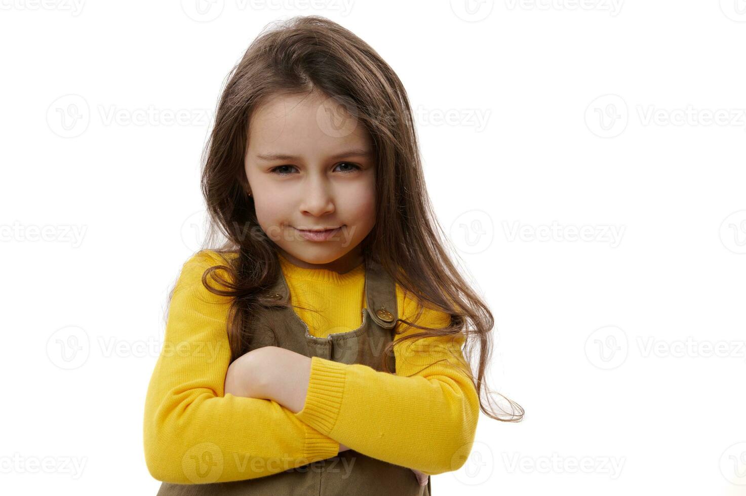 adorável criança menina sorridente alegremente às Câmera, guardando braços guardada, sentindo-me alegre e orgulhoso para ótimo resultados dentro escola foto