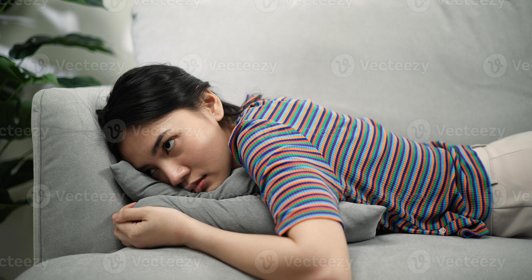 preguiçoso jovem ásia fêmea deitado em uma confortável sofá dentro a vivo quarto às casa foto