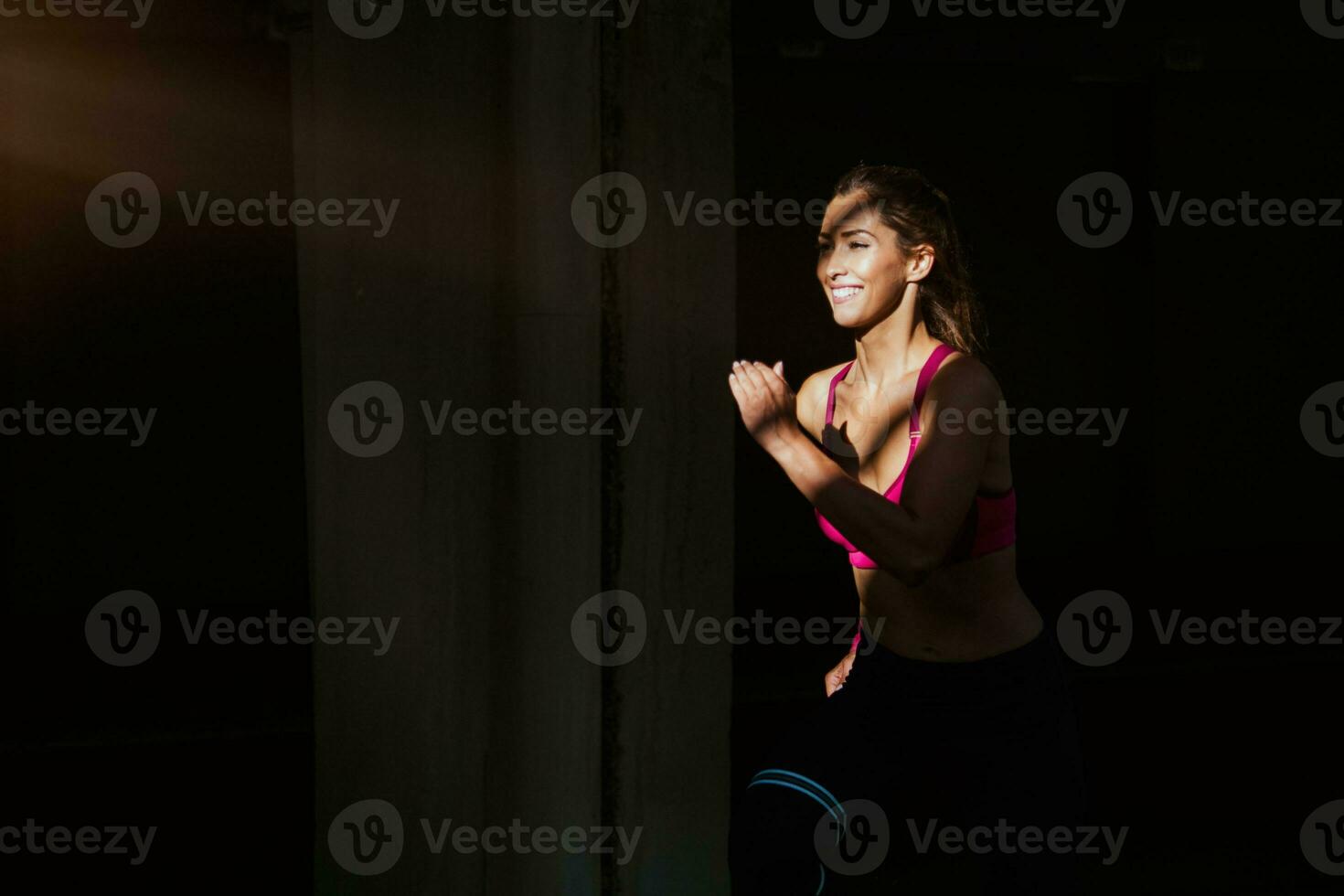 jovem mulher com em forma corpo corrida contra Sombrio fundo. fêmea modelo dentro roupa de esporte exercício mulher ao ar livre fazendo exercite-se exercícios em rua. foto