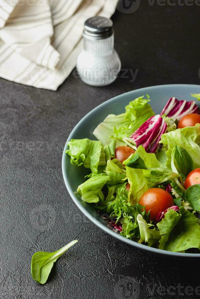 folhas de salada verde em tigela na mesa preta. foto
