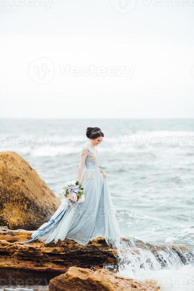 noiva com um buquê de flores na praia foto
