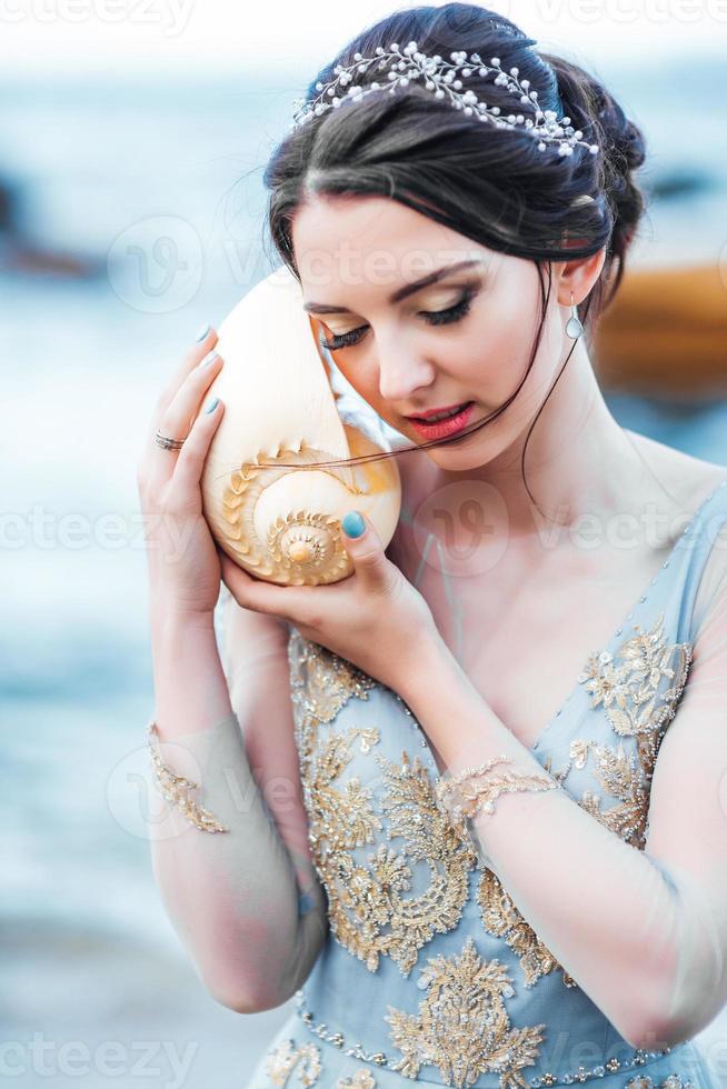 noiva com uma grande concha na praia foto