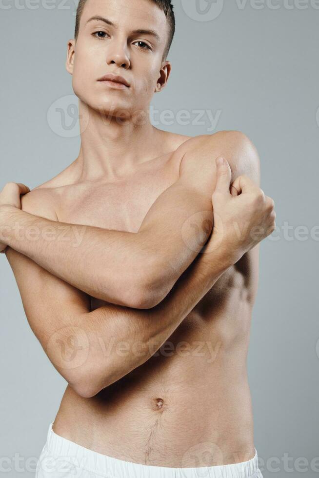 Atlético homem abraços ele mesmo com dele braços bombeado músculos bíceps musculação modelo foto