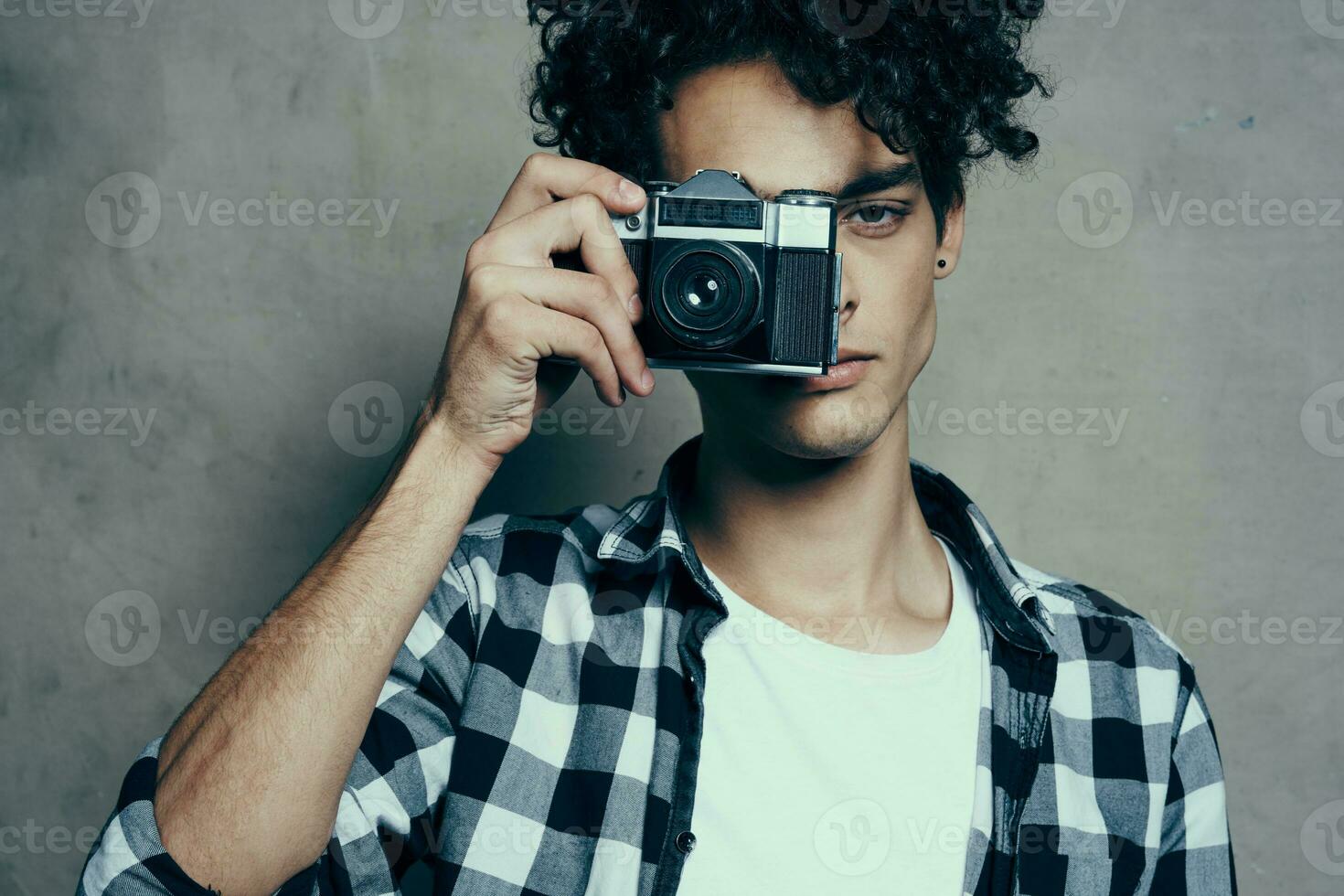 bonito cara com uma Câmera perto dele face e encaracolado cabelo xadrez camisa passatempo fotógrafo foto