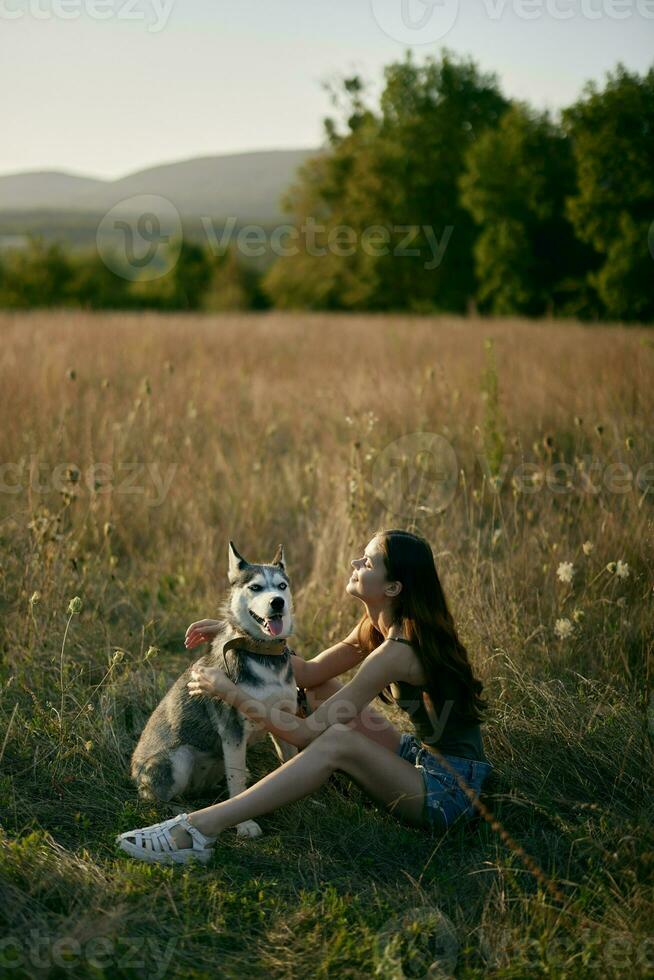 mulher sentado dentro campo com dachshund cachorro sorridente enquanto gastos Tempo dentro natureza com amigo cachorro dentro outono às pôr do sol enquanto viajando foto