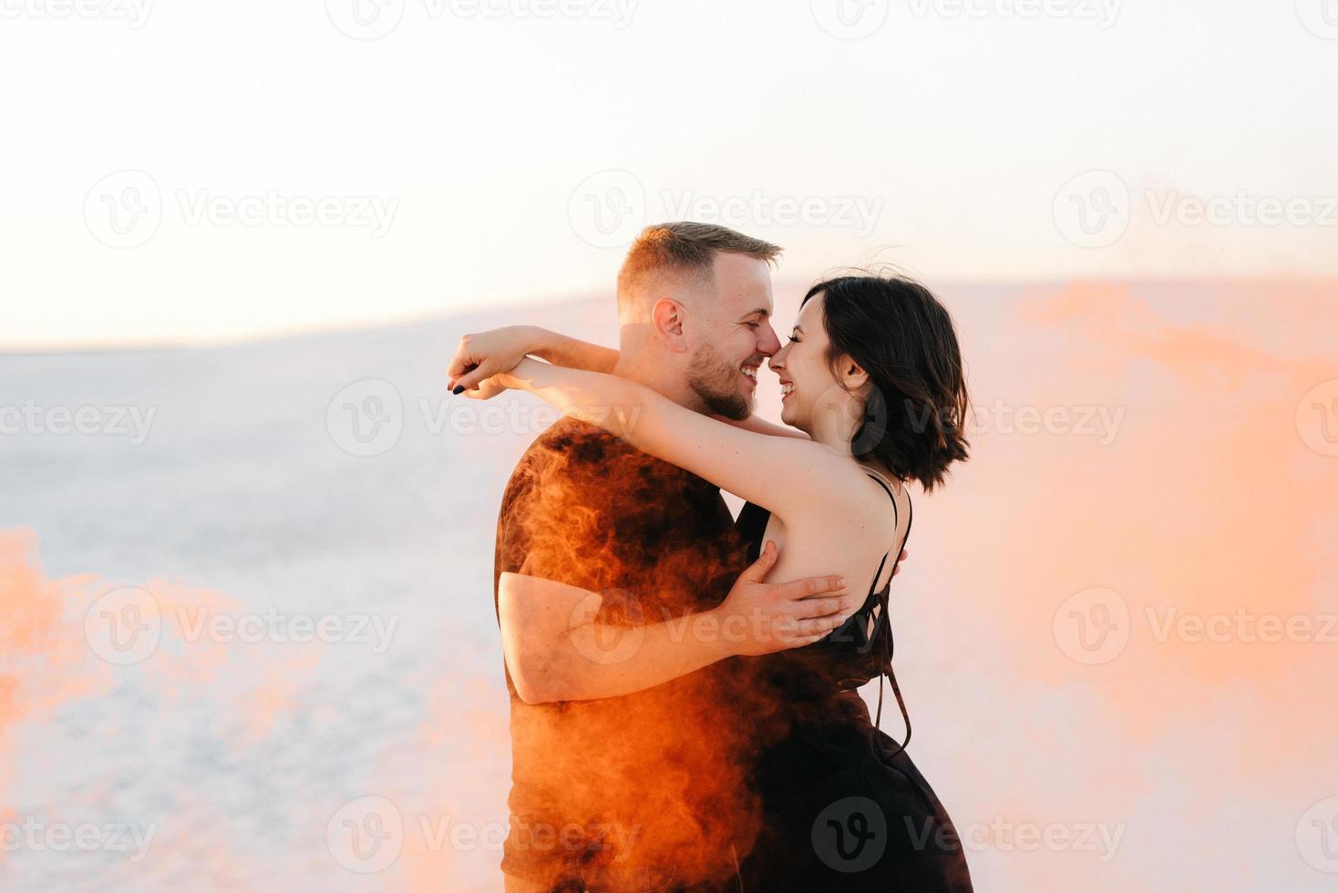 cara e garota em roupas pretas se abraçam e correm na areia branca foto