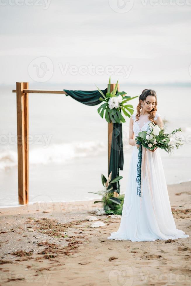 noiva com um buquê de casamento na costa do mar foto