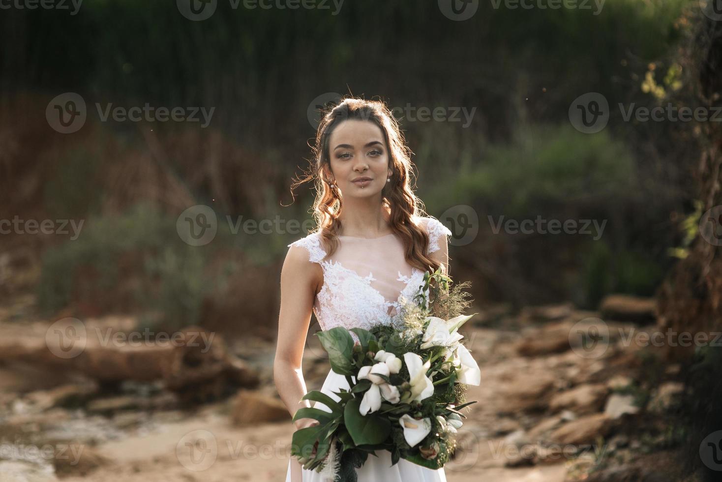 noiva com um buquê de casamento na costa do mar foto