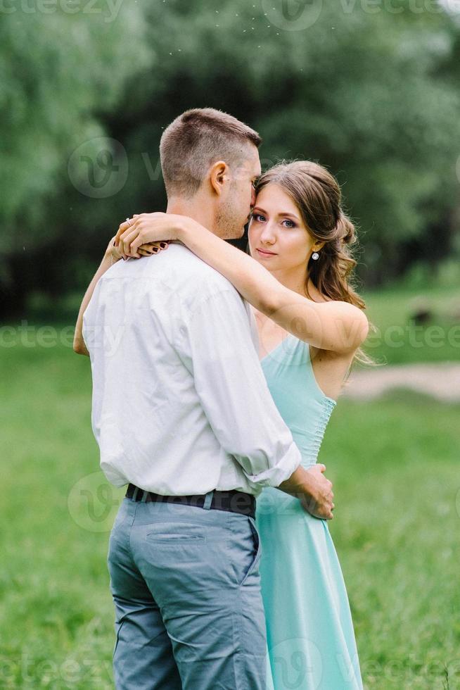 cara feliz em uma camisa branca e uma garota em um vestido turquesa estão caminhando no parque florestal foto