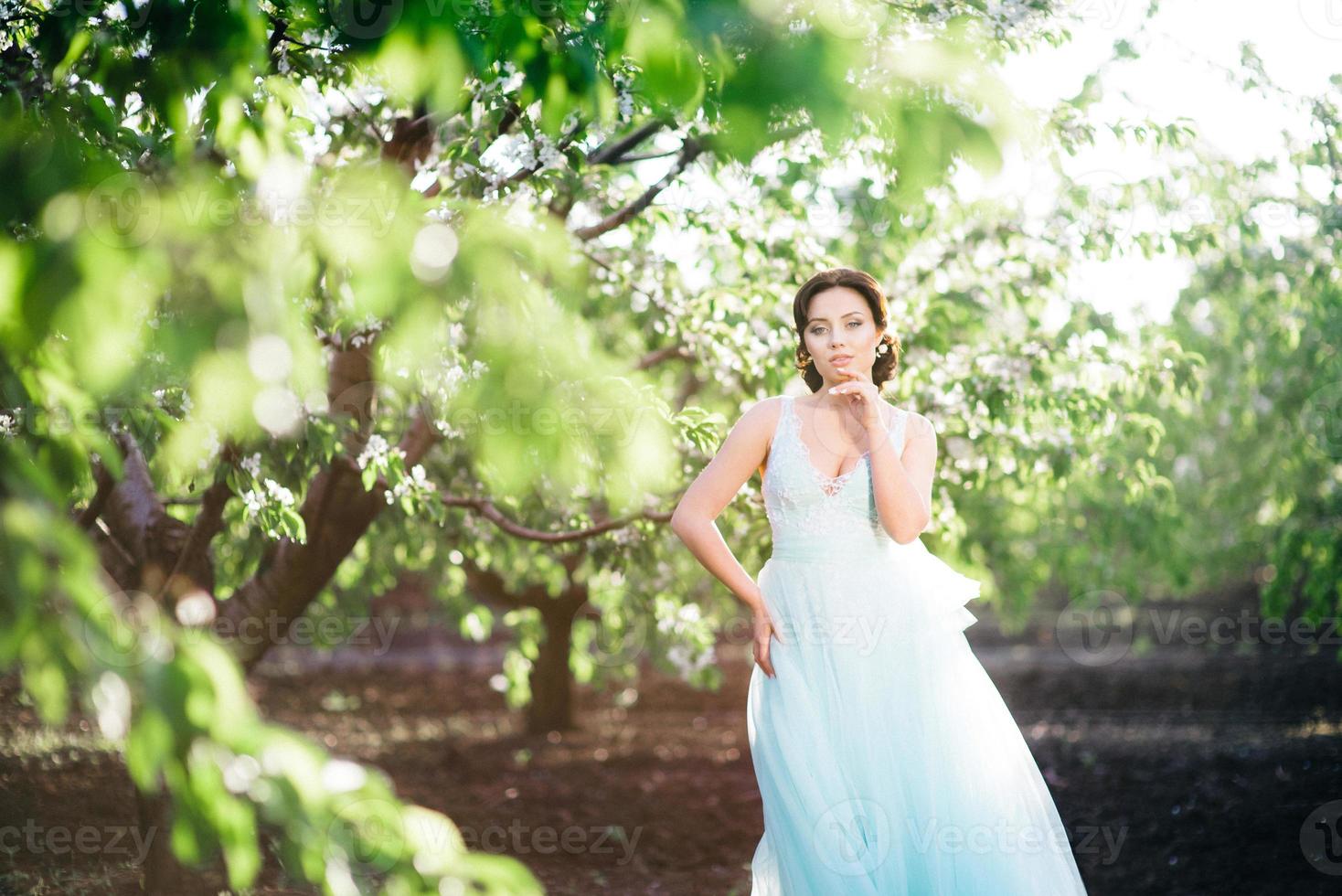 menina morena com um vestido turquesa no jardim primavera foto