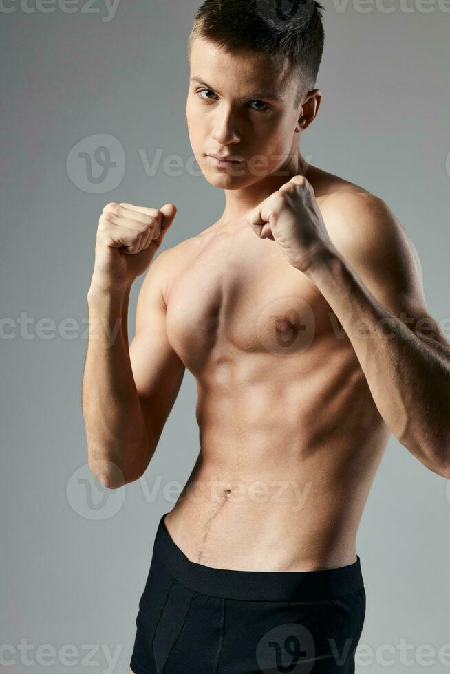 boxer em uma cinzento fundo nu tronco cubos em a estômago fisiculturista ginástica foto