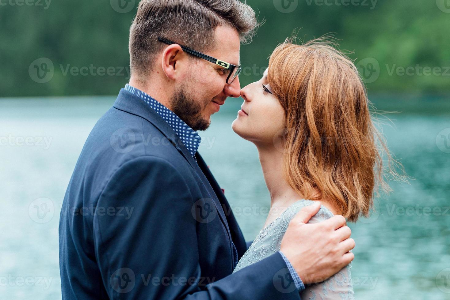 jovem casal passeando perto de um lago cercado por montanhas foto