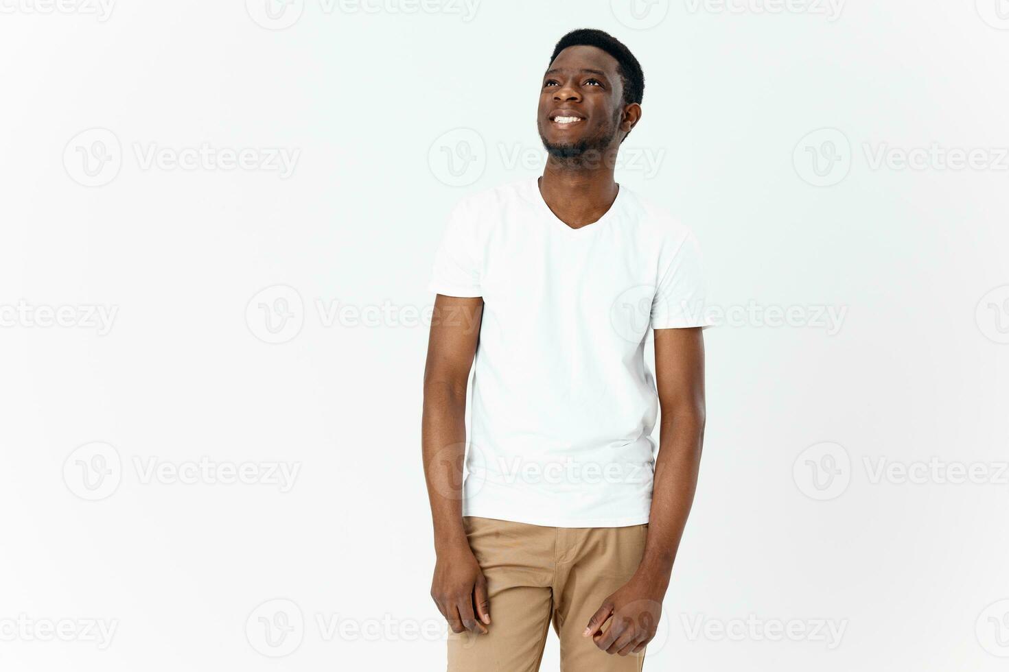 feliz africano homem dentro branco camiseta e bege calça em luz fundo cortada Visão foto