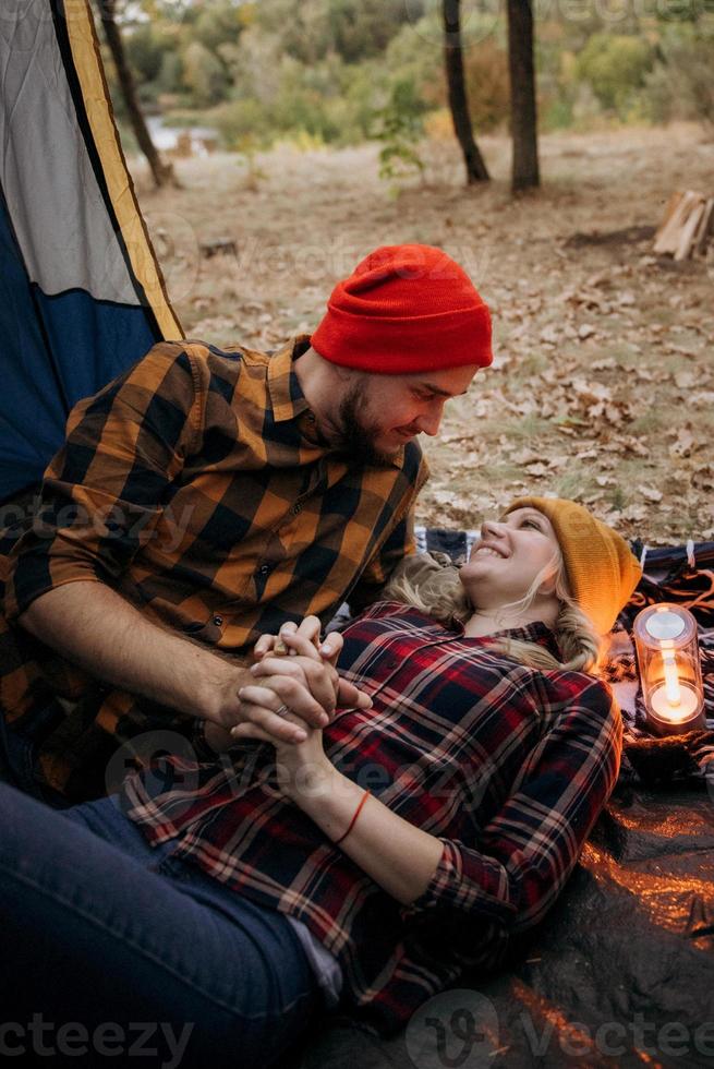 casal jovem, um rapaz e uma rapariga com chapéus de malha brilhantes, pararam num parque de campismo foto