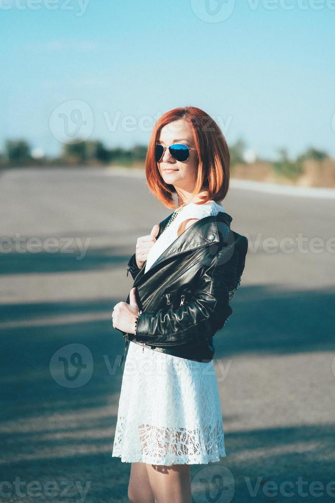 garota ruiva em uma jaqueta preta e óculos azuis foto