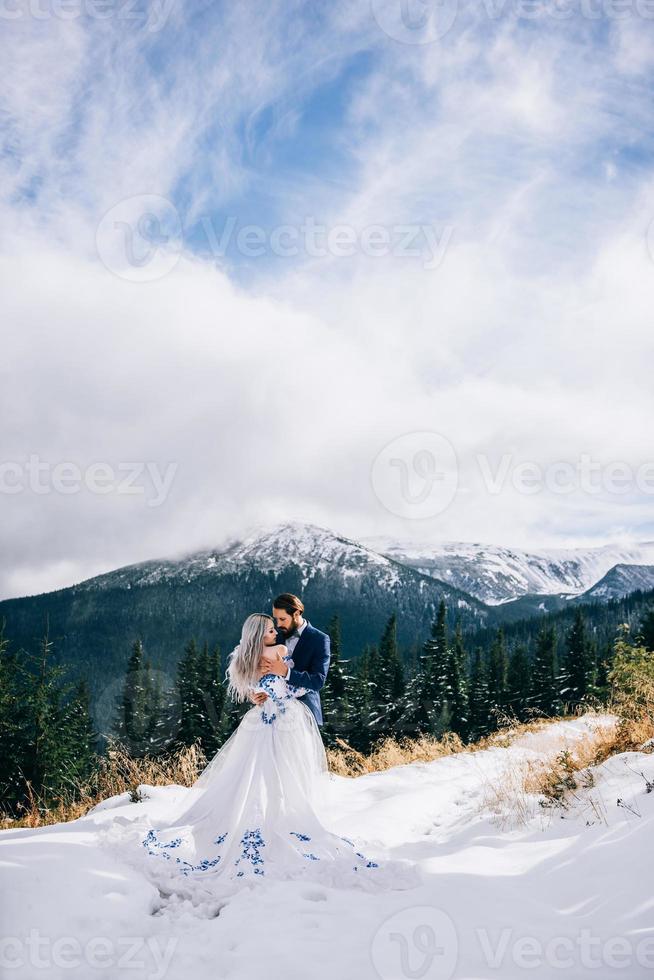 noivo em um terno azul e noiva em branco nas montanhas dos Cárpatos foto