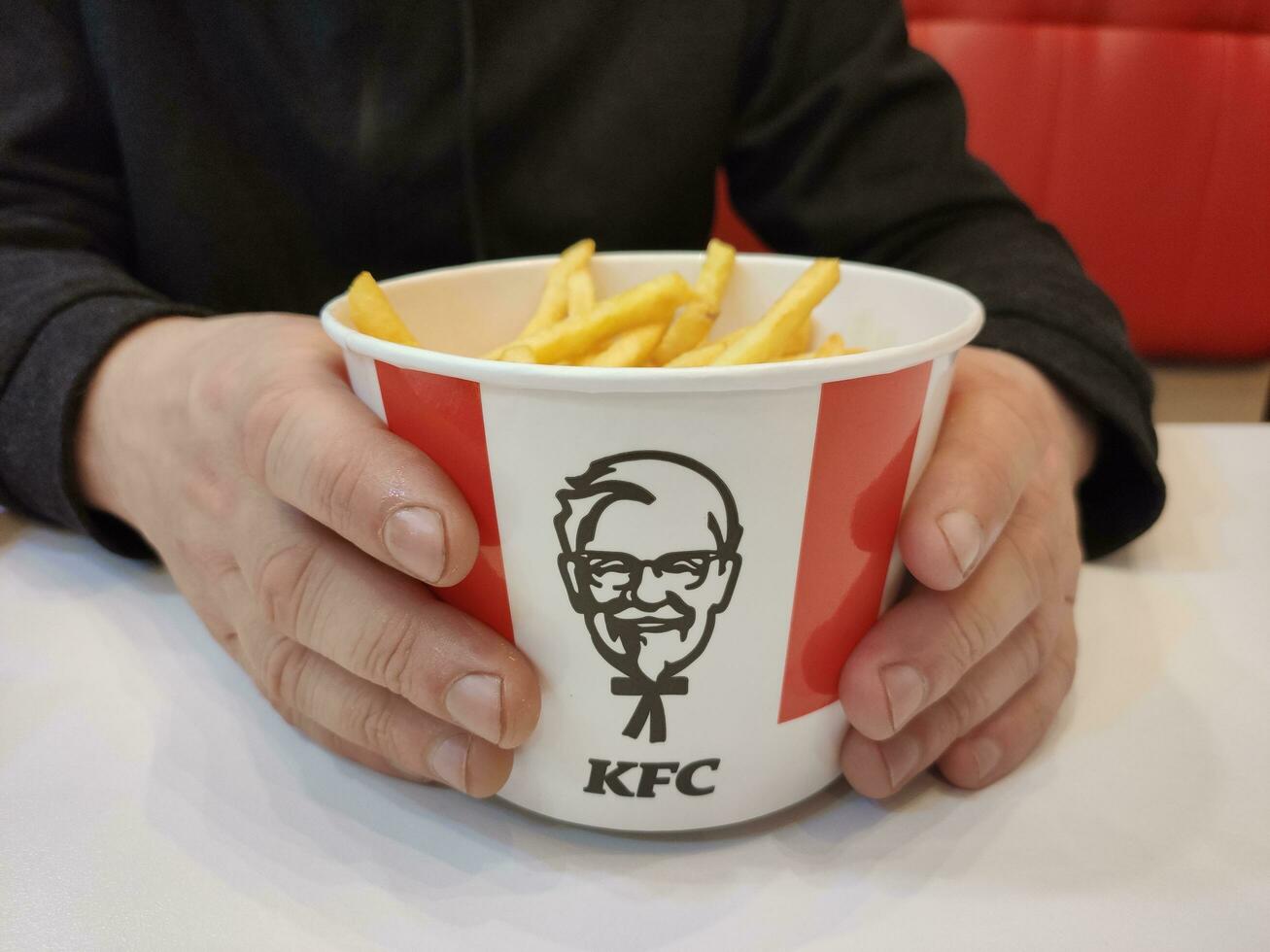 Stavropol, Rússia, abril 2023, velozes Comida restaurante. homem segurando uma caixa do francês fritas foto