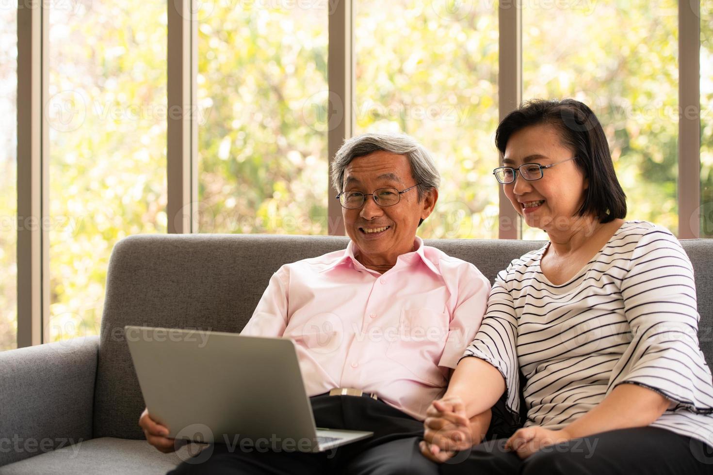 mulher e homem asiático sênior relaxam nas férias no fundo natural da sala de estar com tecnologia moderna foto