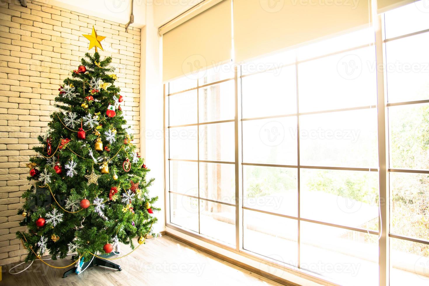 árvore de natal decorada na sala de estar para se preparar para o ano novo. decore a sala de estar e a árvore de natal com uma caixa de bolas vermelhas, bolas douradas, sinos dourados, estrelas de neve, meias. foto