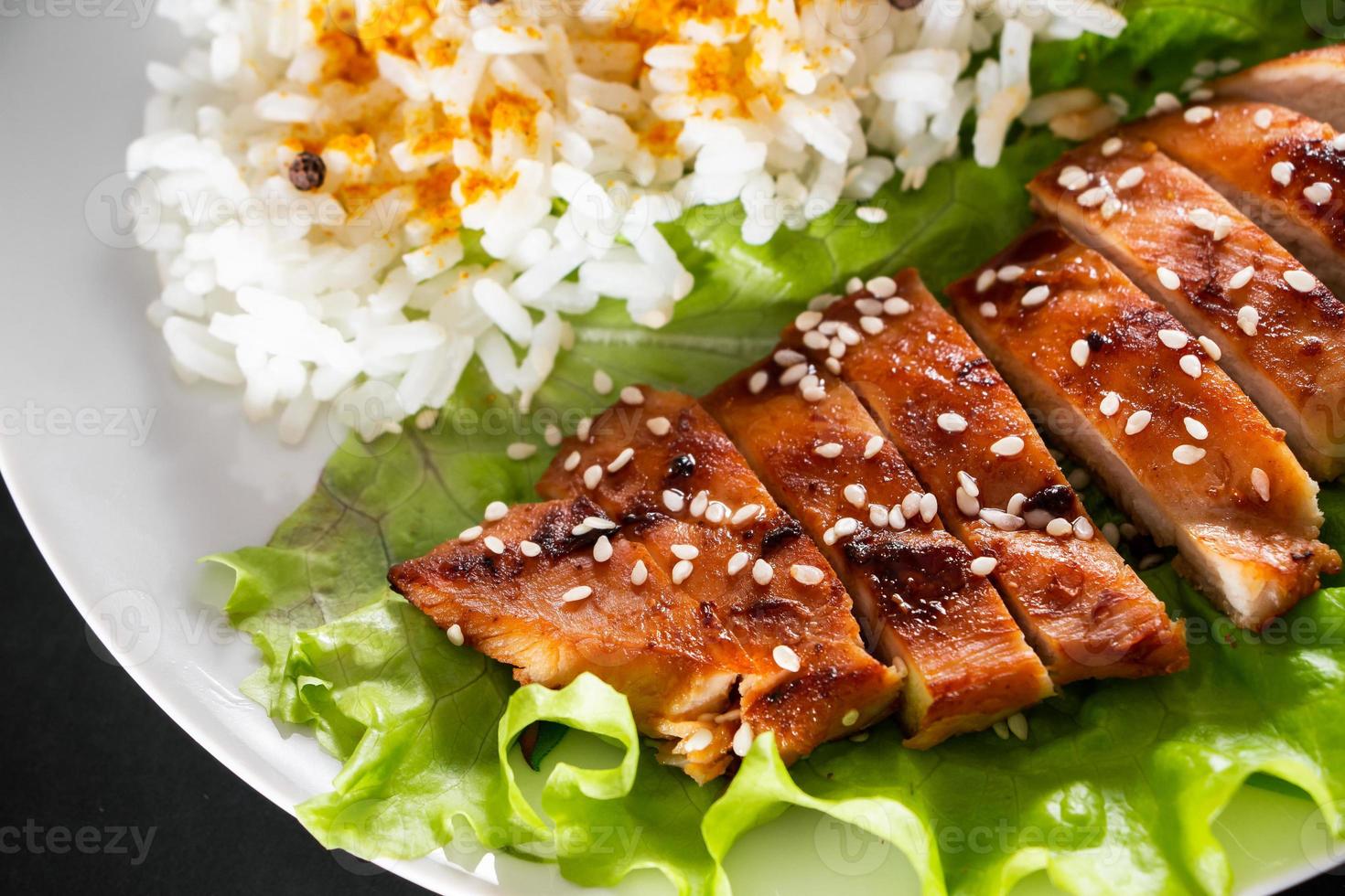 comida caseira frango teriyaki com arroz branco e pimenta em um fundo preto foto