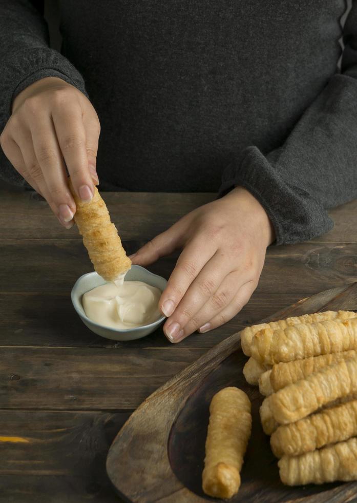 mãos mergulhando um tequeno no molho de queijo foto