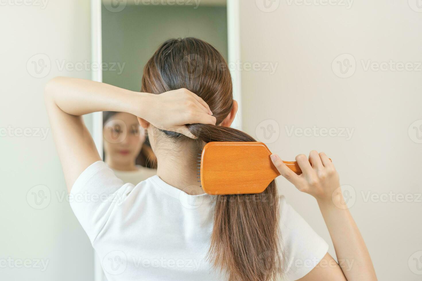 saúde cabelo Cuidado, beleza Maquiagem ásia mulher, menina segurando escova de cabelo e escovar, pentear dela grandes em linha reta cabelo olhando às reflexão dentro espelho dentro manhã rotina depois de salão tratamento, Penteado. foto