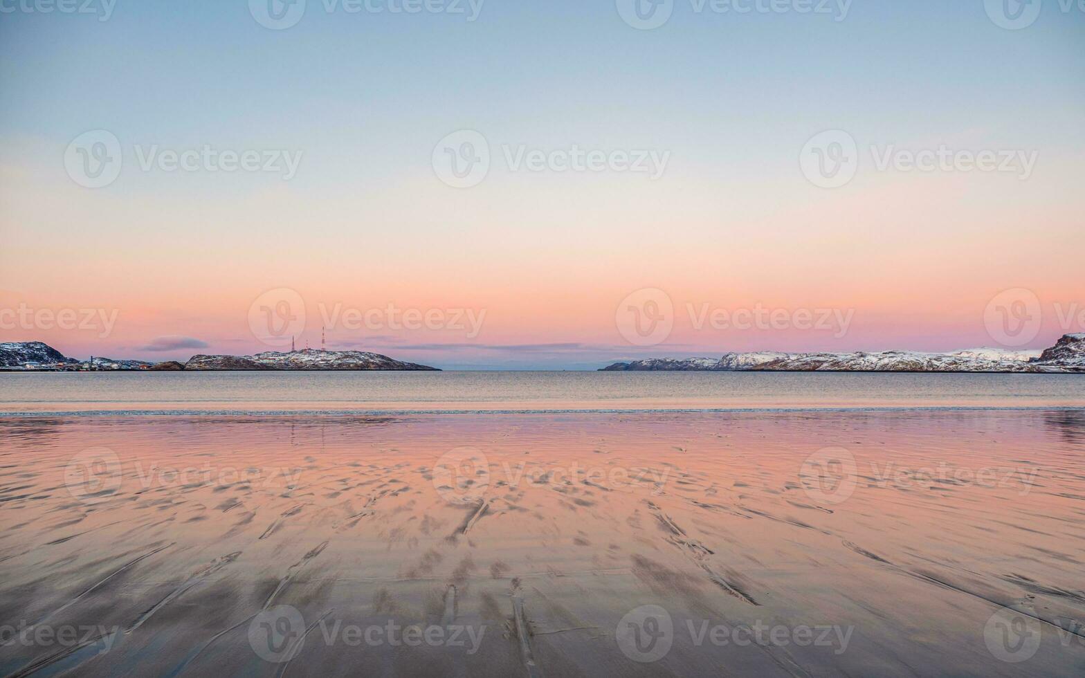 lindo Rosa pôr do sol em a ártico oceano. uma Península com coberto de neve colinas em a horizonte. mar minimalista panorama. foto