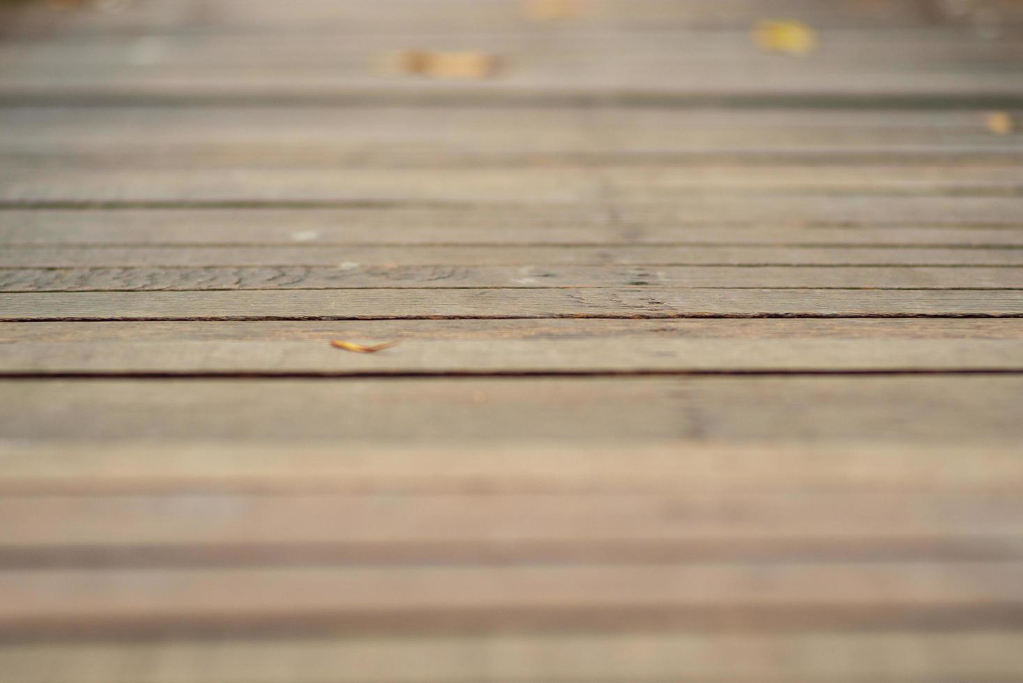 textura abstrata e fundo de passarela de madeira com folhas desfocadas no chão foto