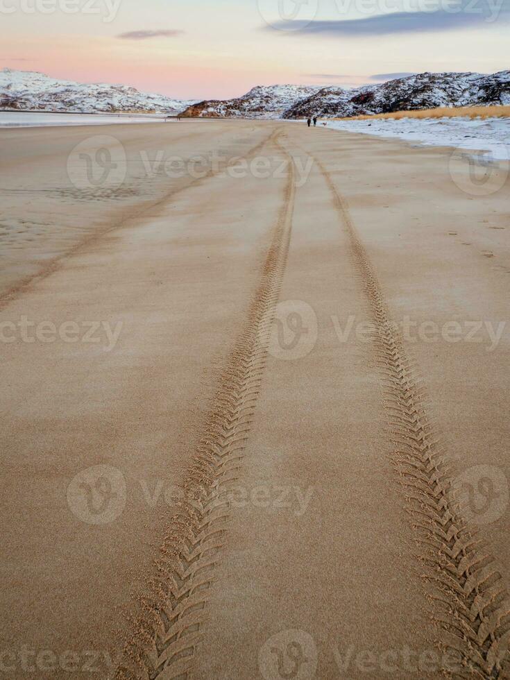 pneu piso marca em a mar areia estendendo para dentro a distância foto