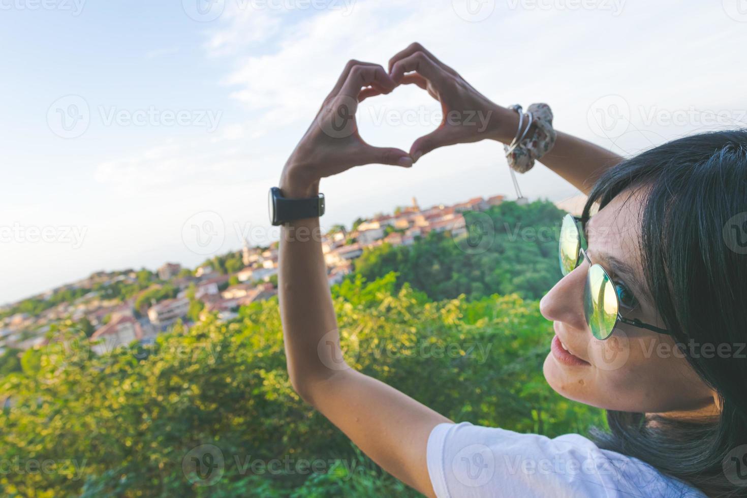 mulher colocando as mãos em formato de coração na frente de uma cidade foto