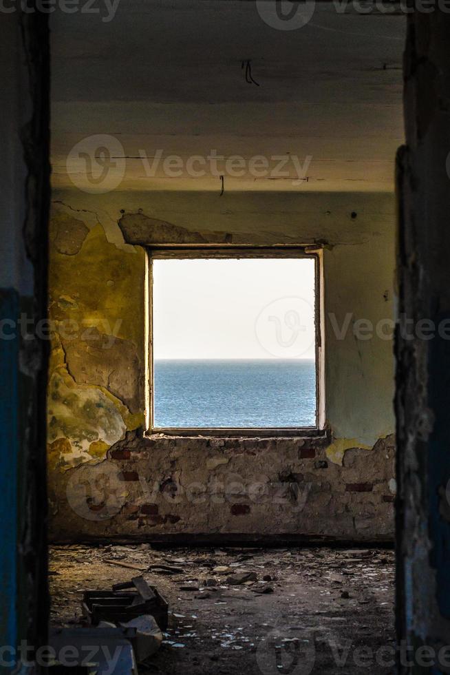 horizonte do mar na janela da sala destruída foto