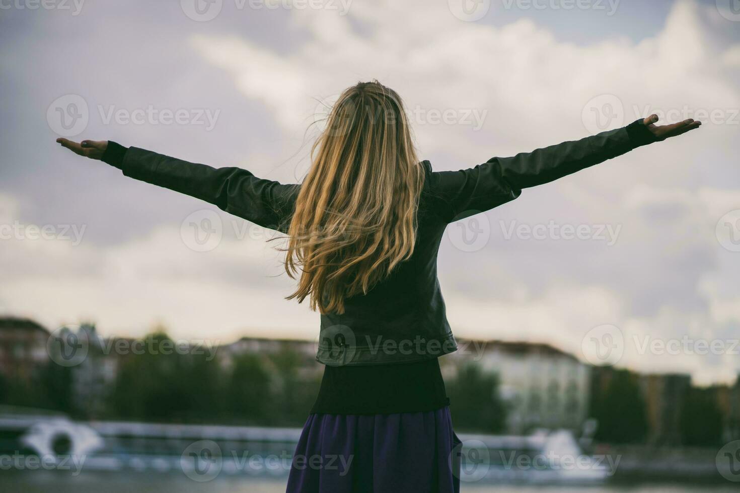 uma feliz jovem mulher com aberto braços dentro a cidade foto