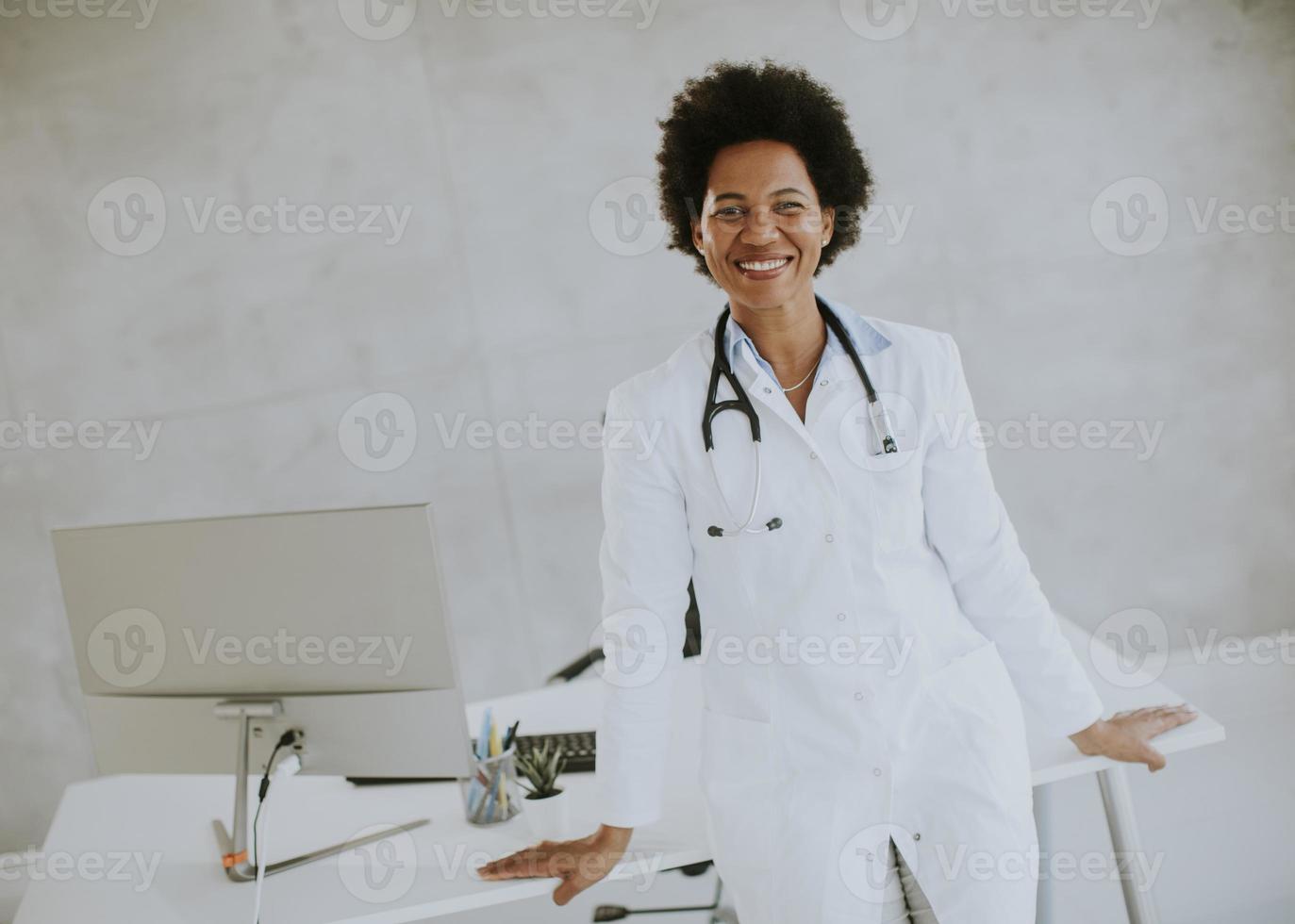médico sorrindo e parado na frente de uma mesa foto