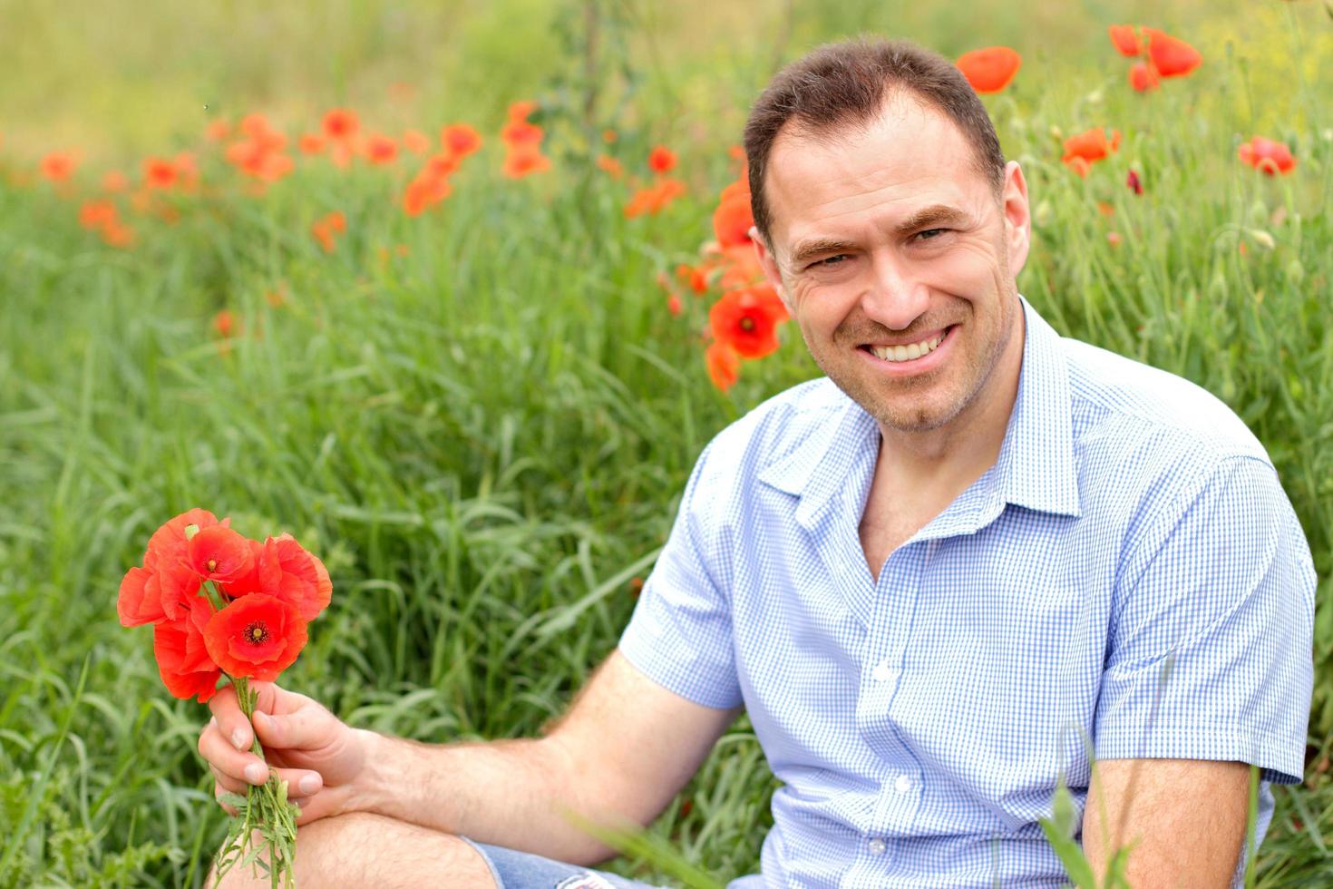 homem sorridente em um campo de papoulas foto