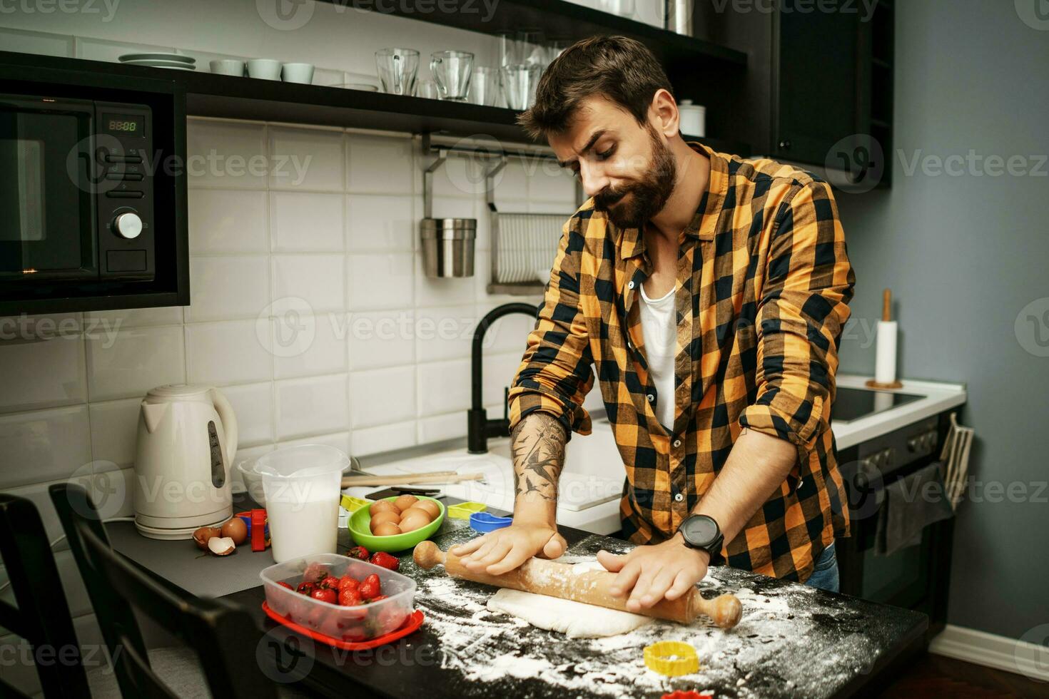 uma homem cozimento biscoitos dentro a cozinha foto